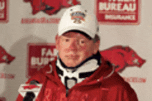 a man wearing a white hat and a red jacket is standing in front of a sign that says fair bureau insurance