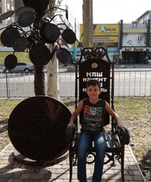 a young boy sits in a chair next to a large coin that says 5