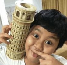 a young boy is sticking his tongue out while holding a model of the leaning tower