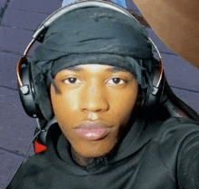 a young man wearing headphones and a head scarf takes a selfie