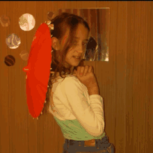 a young girl holding a red umbrella behind her head