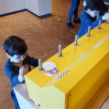 two young boys are playing with a yellow box that has a sticker on it that says ' a ' on it