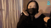 a woman wearing a black mask with the vlive logo on the bottom