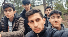 a group of young men are posing for a picture together in the woods .