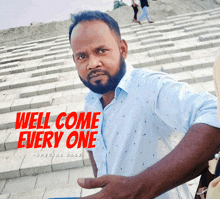 a man with a beard stands in front of a staircase with the words well come every one above him