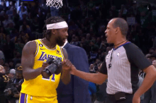 a basketball player wearing a lakers jersey shakes hands with an umpire