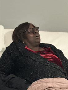 a woman with glasses is laying on a couch