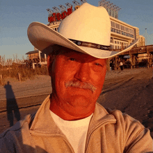 a man wearing a white cowboy hat stands in front of a building that says motel on it