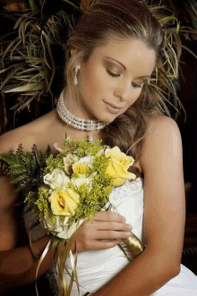 a woman in a white dress is holding a bouquet of yellow roses