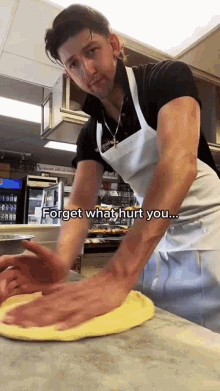 a man in an apron is kneading a dough on a counter with the words " forget what hurt you " below him