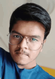 a young man with glasses and a blue shirt looks at the camera