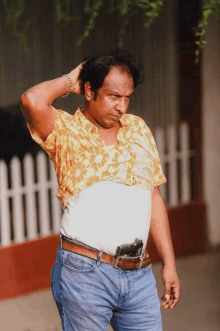 a man is holding a gun in his belt while standing in front of a fence