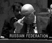 a bald man sitting at a table with a sign that says russian federation