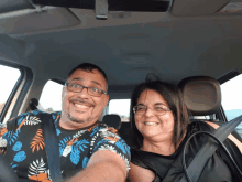 a man and woman are sitting in a car and smiling