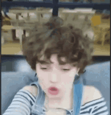 a woman with curly hair is taking a selfie with her mouth open while sitting on a couch .