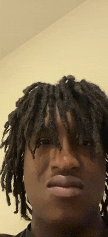 a man with dreadlocks looks at the camera with his mouth open