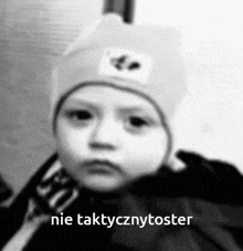 a baby wearing a hat with the words nie taktycznytoster on the bottom right