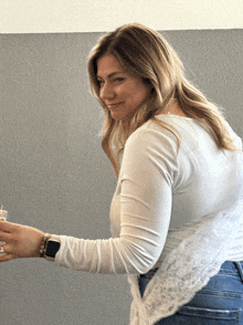 a woman wearing a white shirt and a smart watch smiles