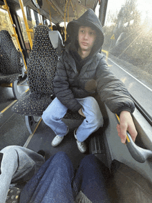 a man in a hooded jacket sits on a bus