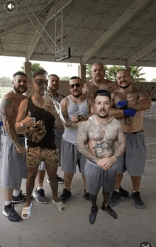 a group of men are posing for a picture and one of them has a tattoo on his arm