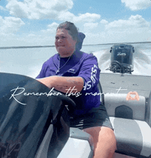 a woman in a purple shirt is driving a boat with the words " remember this moment " written below her