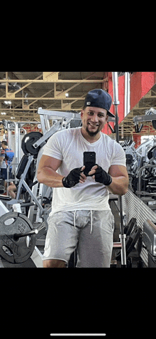 a man in a hat is taking a selfie in a gym .