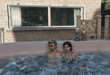 a man and a woman are in a hot tub outside