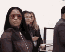 a woman wearing red sunglasses and a burgundy jacket is standing in a line with other people .