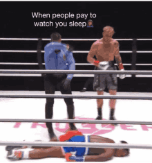 a boxer is laying on the ground in a boxing ring while a referee stands behind him