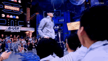 a man is dancing in front of a crowd with a pac-man sign in the background