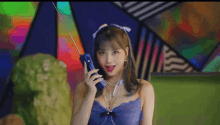 a woman in a blue dress is holding a blue telephone in her hand .