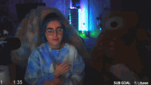 a woman in a blue tie dye sweater is raising her arms in the air while playing a video game