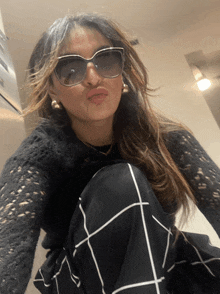 a woman wearing sunglasses and a black sweater is making a funny face