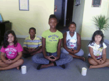 a girl in a hollister shirt sits in a lotus position with other children