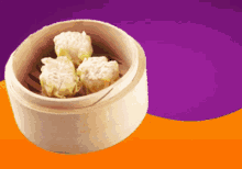 three dumplings in a bamboo steamer on a purple background