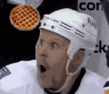 a hockey player with his mouth open and a waffle flying in the air .