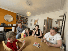 a woman wearing a snoopy shirt is playing a game of uno with her family