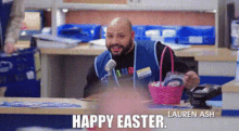 a man is sitting at a counter in a store with a microphone and a basket of easter eggs .