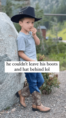 a young boy wearing a cowboy hat and cowboy boots leaning against a rock