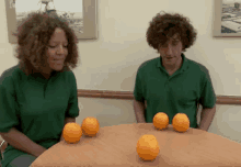 a man and a woman sitting at a table with oranges on it