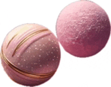 two pink balls with gold swirls on them are sitting next to each other on a white background .