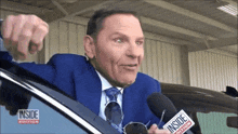 a man in a suit and tie is talking into a microphone that says inside edition on it