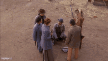 a group of men are gathered in a dirt field with the words " shall we begin " written above them