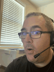 a man wearing glasses and a headset looks at the camera