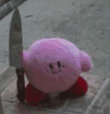 a pink kirby stuffed animal is holding a knife in its mouth .