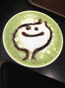 a cup of green tea with a smiley face drawn on the top