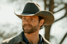 a man with a beard wearing a cowboy hat and a jacket
