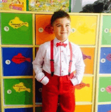 a young boy is wearing red suspenders and a bow tie .