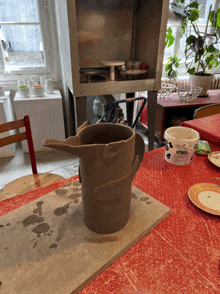 a pitcher on a table next to a container of clay