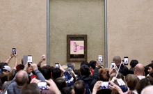 a crowd of people taking pictures of a painting with a pink background